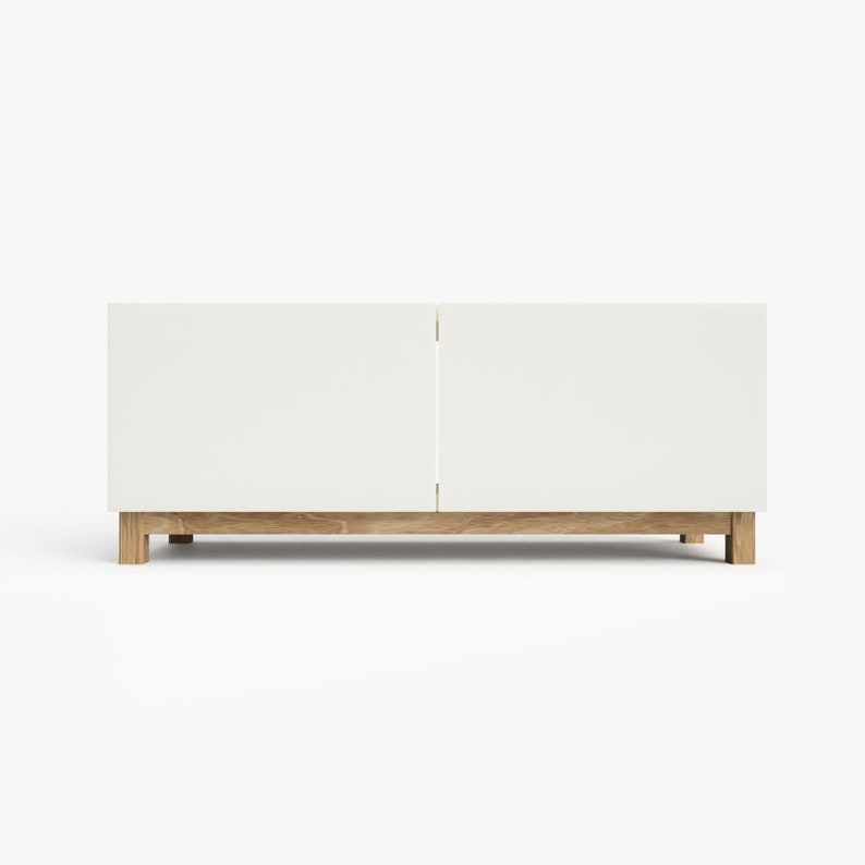 May include: White cabinet with two doors and a wood base. The cabinet is sitting on a white surface.