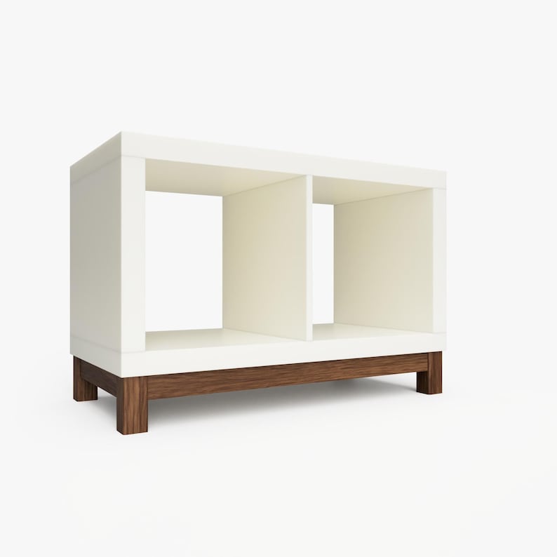 May include: White bookshelf with two open shelves and a brown wood base. The bookshelf is made of wood and has a modern design.