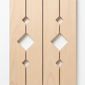 May include: Two rectangular light-colored wooden panels placed side by side. Each panel features a vertical arrangement of three diamond-shaped cutouts, with a larger central diamond flanked by two smaller diamonds, creating a symmetrical pattern.
