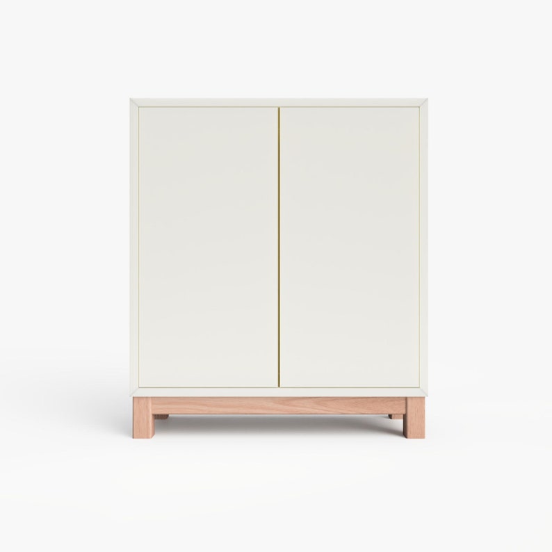 May include: A white cabinet with two doors and a wooden base. The cabinet has a simple, modern design.