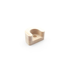 May include: A light-coloured wooden bracket with a curved top and a cylindrical hole. The bracket is made of layered wood and has a smooth, natural finish. The design is simple and modern, suitable for various home decor styles.