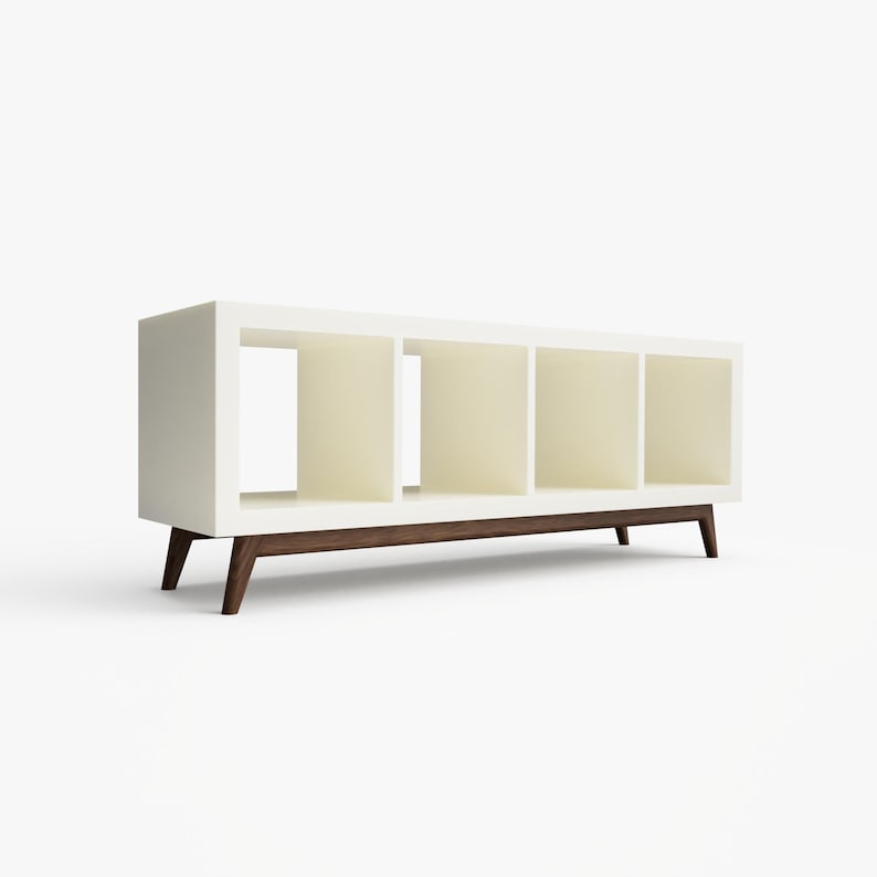 May include: White bookshelf with four open shelves and a dark wood base. The bookshelf has a modern design with angled legs.