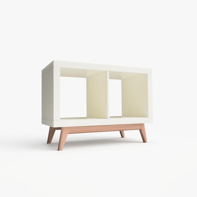 May include: White bookshelf with two open shelves and a wooden base. The bookshelf has a modern design with a simple, clean look.