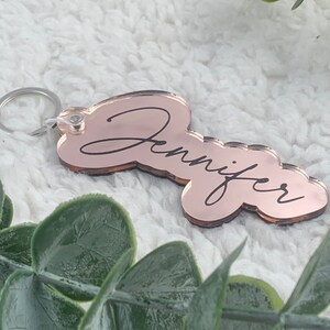 Peut inclure: Porte-clés en or rose avec le nom Jennifer écrit en cursive.