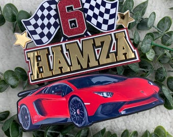 以下が含まれることがあります： 金色の文字で「HAMZA」と書かれた赤いスポーツカーのケーキトッパー。トッパーには、赤いグリッターの「6」、市松模様の旗、金の星も付いています。車をテーマにした誕生日に最適です。