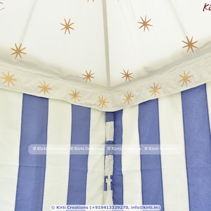 May include: A white and blue striped canopy tent with gold stars printed on the white fabric. The tent has a white fabric border with gold stars printed on it. The text "Kirti Creations" is printed on the fabric.