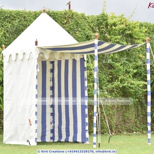 May include: A white and blue striped canopy tent with a white canvas roof. The tent is set up outdoors with a green lawn and a hedge in the background. The tent has a white fabric awning and is supported by wooden poles.