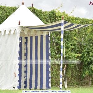 Pode incluir: Uma tenda de dossel listrada de branco e azul com uma parede de tecido branco. A tenda tem uma estrutura de madeira e está montada em uma área gramada com vegetação verde no fundo.