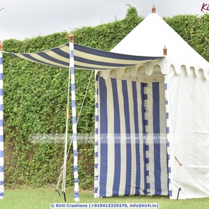 May include: A white and blue striped canopy tent with a white canvas roof. The tent is set up in a grassy area with a green hedge in the background. The tent has a white fabric awning with blue stripes.