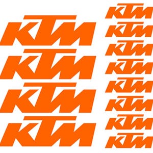 May include: A sheet of orange KTM logo stickers. The KTM logo features the letters "KTM" in a bold, sans-serif font. The stickers are arranged in rows and columns, with the KTM logo repeated multiple times.