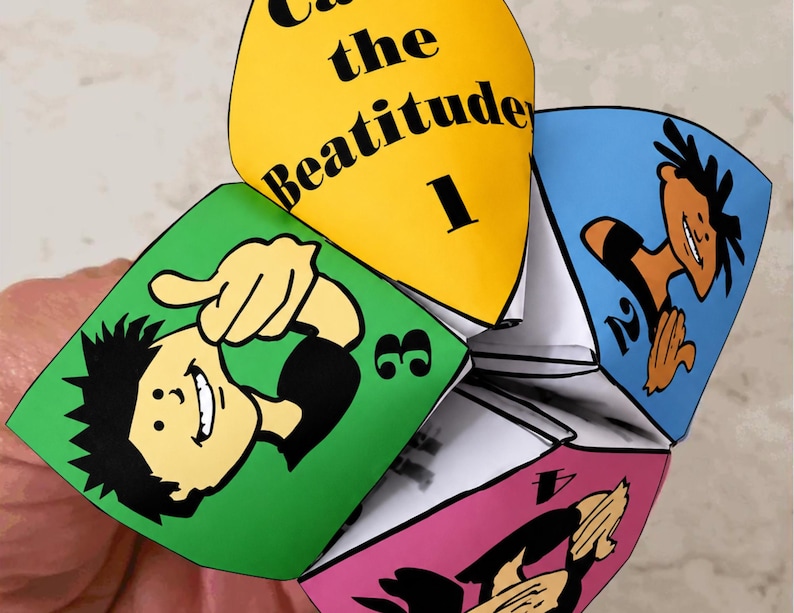 May include: A colorful paper fortune teller with the text "Call the Beatitude 1" on a yellow panel. Other panels are green, blue, and pink, each with a cartoon illustration and a number. The fortune teller is held in a person's hand.
