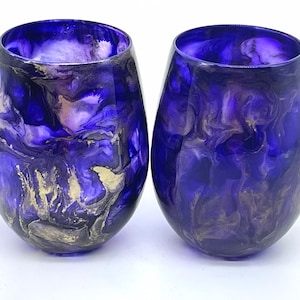 May include: Two clear glass wine glasses with a swirling purple, white, and gold abstract design.