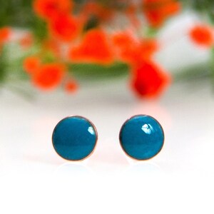 Könnte beinhalten: Ein Paar kleine, runde, türkisfarbene Ohrstecker. Die Ohrringe sind in einer silbernen Fassung gefasst.