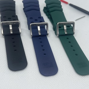 Peut inclure: Trois bracelets de montre en noir, bleu et vert. Chaque bracelet est dot&eacute; d'une boucle argent&eacute;e avec le mot "SEIKO" imprim&eacute; sur le bracelet.