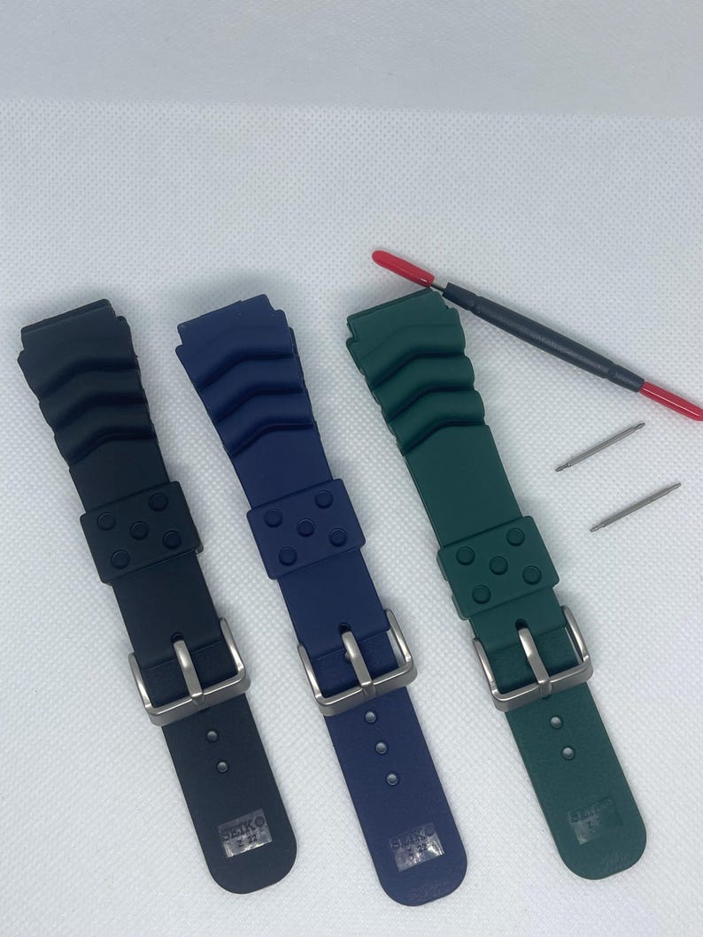 Peut inclure: Trois bracelets de montre en noir, bleu et vert. Chaque bracelet a un design textur&eacute; et une boucle argent&eacute;e. Les bracelets sont marqu&eacute;s "SEIKO" au dos.