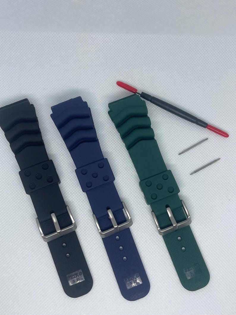 Peut inclure: Trois bracelets de montre en noir, bleu et vert. Chaque bracelet est dot&eacute; d'une boucle argent&eacute;e et est fabriqu&eacute; dans un mat&eacute;riau en caoutchouc textur&eacute;. Les bracelets sont dispos&eacute;s sur une surface blanche.