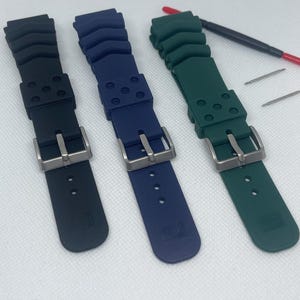 Peut inclure: Trois bracelets de montre en noir, bleu et vert. Chaque bracelet est dot&eacute; d'une boucle argent&eacute;e et est fait d'un mat&eacute;riau en caoutchouc textur&eacute;.
