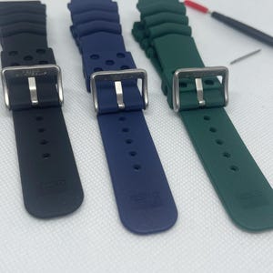 Peut inclure: Trois bracelets de montre en noir, bleu et vert. Chaque bracelet est fait d'un mat&eacute;riau en caoutchouc textur&eacute; et poss&egrave;de une boucle en acier inoxydable. Les bracelets sont tous de la m&ecirc;me taille et du m&ecirc;me style.