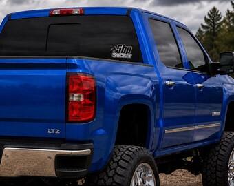 Puede incluir: Una camioneta azul brillante con parachoques trasero cromado y emblema LTZ. Un adhesivo blanco está aplicado en la ventana trasera lateral, mostrando el texto +5hp Sticker en una fuente negrita y estilizada sobre el vidrio tintado oscuro.