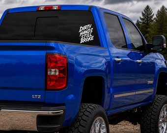 Puede incluir: Una camioneta azul brillante con una calcomanía de vinilo blanca en la ventana trasera que dice Dirty Hands Still Broke en una fuente estilizada. La camioneta cuenta con un parachoques cromado, neumáticos todoterreno y una insignia LTZ.