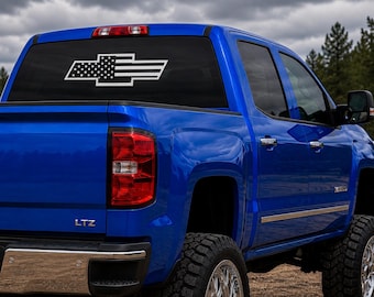Puede incluir: Una camioneta azul brillante con una calcomanía blanca en la ventana trasera. La calcomanía muestra el logotipo de Chevrolet en forma de pajarita estilizado con las estrellas y rayas de la bandera estadounidense. La camioneta tiene parachoques cromado.