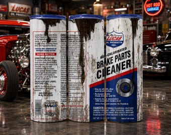 Puede incluir: Un vaso cilíndrico con un diseño gráfico que imita una lata de limpiador de frenos Lucas Oil. La superficie blanca tiene una textura desgastada con gotas de aceite negro, detalles en azul y rojo, y texto detallado del producto.
