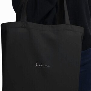 May include: A black tote bag with a white embroidered design that says "bite me".