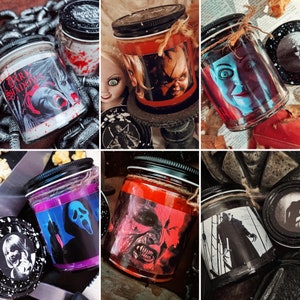 May include: Set of nine candles with horror movie themes. The candles are in glass jars with black lids and feature various characters and scenes from popular horror films. The candles are arranged in a grid pattern on a dark background.