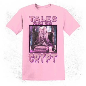 K&ouml;nnte beinhalten: Pinkes T-Shirt mit einem Grafikdruck einer gruseligen Figur aus "Tales from the Crypt" mit dem Titel und Logo der Show.