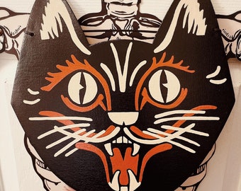 Op de afbeelding: Zwart-witte illustratie van een kat met oranje ogen en een grote, open mond. Het gezicht van de kat is op een zwarte achtergrond geschilderd.