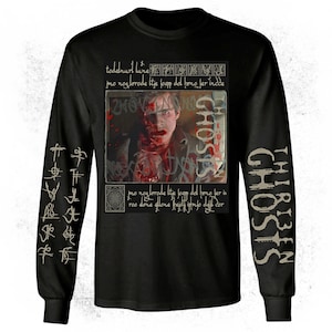 May include: Black long-sleeved shirt with a graphic from the film "Thirteen Ghosts." The shirt features a distressed image of a person covered in blood, with the word "GHOSTS" and other text. The sleeves have additional text.