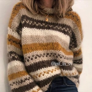 May include: A striped knit jumper with brown, white and mustard yellow stripes. The jumper has a fair isle pattern with small white hearts on the brown stripes. The jumper is shown on a person wearing blue jeans. The text "@knit_by_siv" is visible on the jumper.