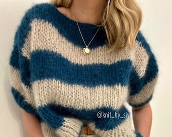 May include: A teal and cream striped knit sweater with a loose fit and short sleeves. The sweater is made with a fuzzy yarn and has a relaxed, casual style. The text "@knit_by_siv" is visible on the sweater.