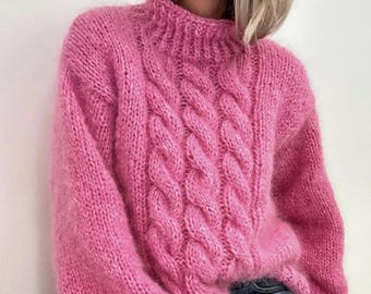 May include: A pink fluffy knit jumper with a cable knit design.