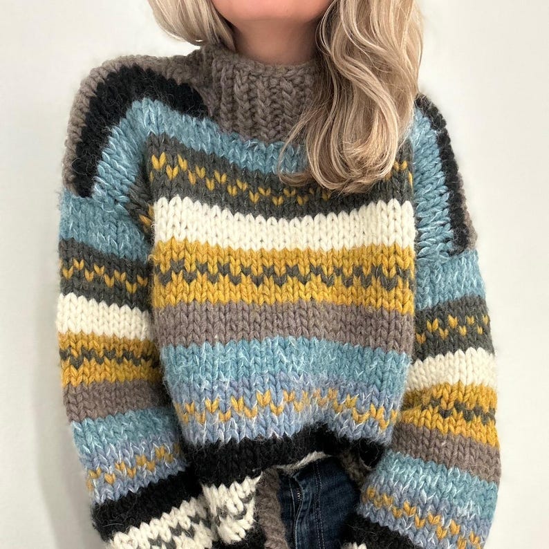 May include: A chunky knit sweater with a high collar. The sweater features horizontal stripes in various colors, including black, blue, white, yellow, and gray. The thick yarn creates a textured appearance, perfect for cold weather.