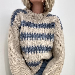 May include: A beige and blue striped knitted jumper with a crew neck. The jumper has a textured knit and a loose fit.