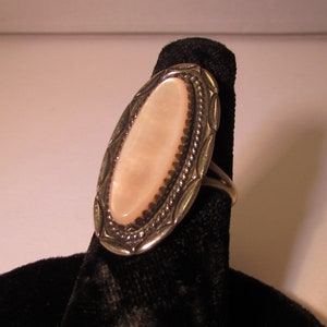 May include: A silver ring with an oval shaped pink mother of pearl stone set in a detailed silver design.