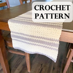 Peut inclure: Un chemin de table crocheté avec un motif rayé beige et gris. Le chemin de table est posé sur une table en bois avec le texte "CROCHET PATTERN" en lettres noires sur fond blanc.
