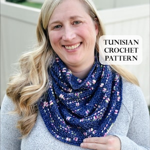 May include: A woman wearing a navy blue Tunisian crochet cowl with a floral pattern. The cowl is around the neck and shoulders. The text "TUNISIAN CROCHET PATTERN" is in a white box in the upper right corner. The woman is wearing a gray sweater.