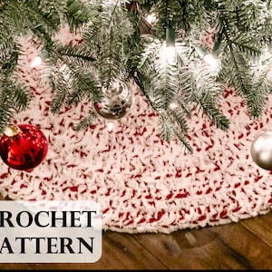 Puede incluir: Una falda de árbol de Navidad de crochet blanca y roja con el texto "CROCHET PATTERN" en la parte inferior. La falda se coloca debajo de un árbol de Navidad con adornos y luces.