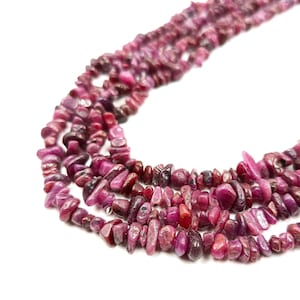 Peut inclure: Un brin de pierres précieuses en rubis rose, avec une finition lisse et polie. Les éclats sont de forme et de taille irrégulières et sont enfilés sur un fil transparent. Le brin mesure environ 46 cm de long.