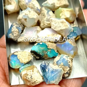 Puede incluir: Una colecci&oacute;n de piedras preciosas de &oacute;palo en bruto en varios tonos de azul, verde y blanco. Los &oacute;palos est&aacute;n en una bandeja de metal peque&ntilde;a y est&aacute;n listos para ser utilizados en la fabricaci&oacute;n de joyas.