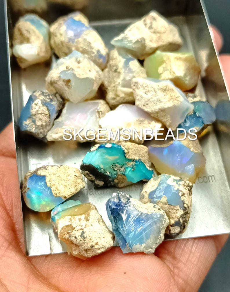 Puede incluir: Una colecci&oacute;n de piedras preciosas de &oacute;palo en bruto en varios tonos de azul, verde y blanco. Los &oacute;palos est&aacute;n en una bandeja de metal peque&ntilde;a y est&aacute;n listos para ser utilizados en la fabricaci&oacute;n de joyas.