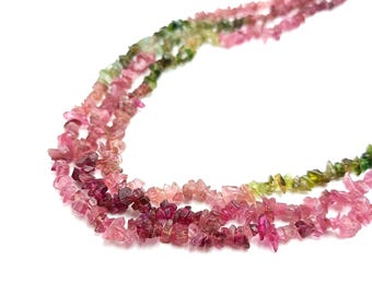 May include: A multi-strand necklace composed of irregular, tumbled chip beads. The beads feature a gradient of colors ranging from deep magenta and vibrant pink to soft rose and light green, creating a textured, organic appearance throughout.