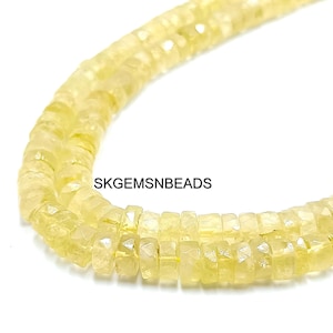 May include: Close-up of a strand of light yellow gemstone beads. The beads are rectangular with faceted edges, creating a sparkling effect. The beads are strung together, forming a necklace or bracelet.