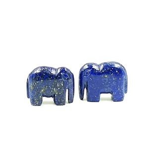 May include: Two small, carved elephant figurines. The elephants are a deep blue color with flecks of gold throughout, giving them a textured appearance. They are standing upright with their trunks down.