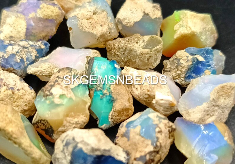 Puede incluir: Una colecci&oacute;n de piedras de &oacute;palo natural en bruto en varios tonos de azul, verde, blanco y marr&oacute;n. Las piedras tienen una forma irregular y una superficie rugosa y texturizada.