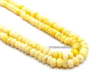 May include: Close-up of a necklace made of yellow and off-white beads. The beads are small, round, and strung together. The necklace is displayed against a white background. The text "SKGEMSNBEADS" is visible.