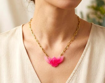 May include: A gold-toned chain necklace featuring a bright pink, carved bird-shaped pendant. The pendant has a stylized wing design and is suspended from a series of elongated, rectangular metal links that form the main chain of the necklace.
