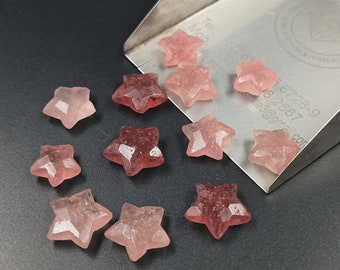 Può includere: Dieci pietre preziose a forma di stella di colore rosa, alcune con una tonalità rosa più scura, sono sparse su una superficie argentata. La superficie ha il testo "Tel. (66) 6728-9 18 2667 stones3@gmail.com"